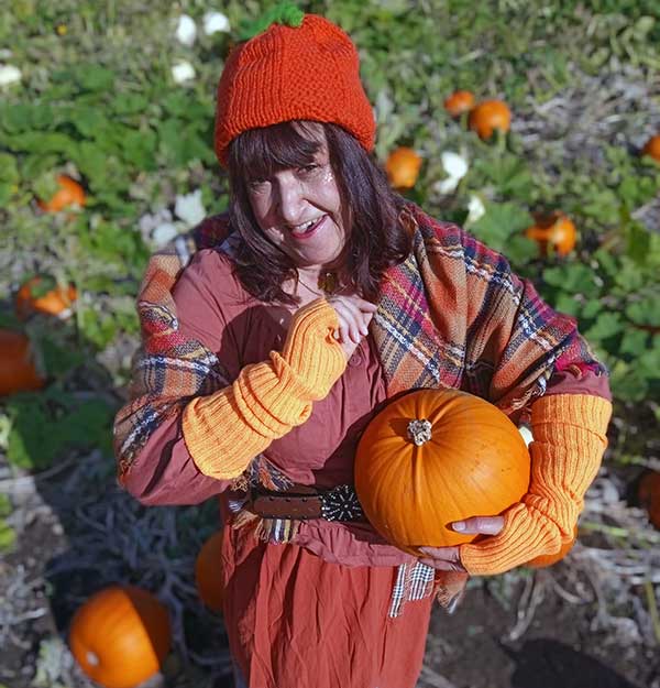 A woman in a red hat is standing in a pumpkin field